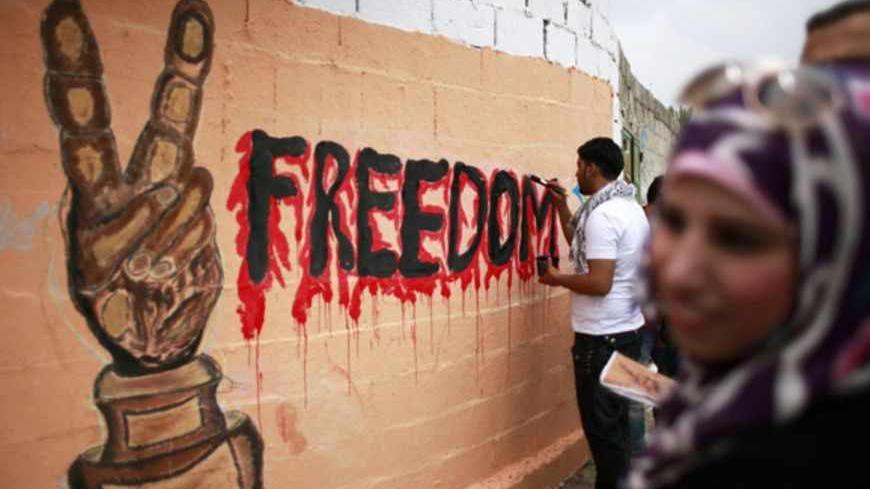 A Palestinian artist paints a mural in Gaza City in support of Palestinian prisoners on a hunger strike in Israeli jails May 14, 2012. One in three of the 4,800 Palestinians serving time in Israeli jails began refusing food on April 17 in protest against detention without trial and to demand better conditions like an increase in family visits and ending solitary confinement. REUTERS/Suhaib Salem (GAZA - Tags: POLITICS CIVIL UNREST) - RTR321GT
