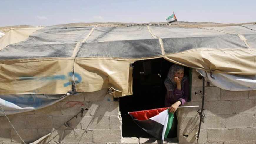 A Palestinian woman holds a Palestinian flag in the West Bank village of Susiya June 24, 2012. Susiya the Israeli settlement enjoys well-watered lawns, humming electricity, and the protection of a mighty state. One rocky hill away, Susiya the Palestinian village is parched and doomed. Picture taken June 24, 2012. To match Feature ISRAEL-PALESTINIANS/DEMOLITION   
REUTERS/Baz Ratner (WEST BANK - Tags: POLITICS TPX IMAGES OF THE DAY) - RTR347HZ