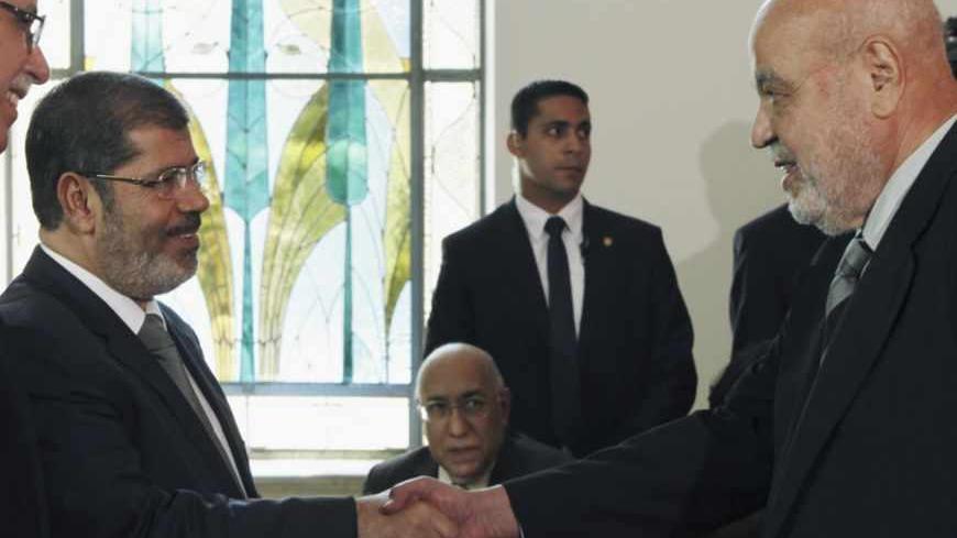 Egypt's President Mohamed Mursi (L) shakes hand with Egypt's Justice Minister Ahmed Mekky during the visit of Libyan Prime Minister Abdul Raheem al-Keeb, who is leading a Libyan delegation of government ministers, at the presidential palace in Cairo, August 6, 2012. REUTERS/Amr Abdallah Dalsh  (EGYPT - Tags: POLITICS) - RTR36A2J