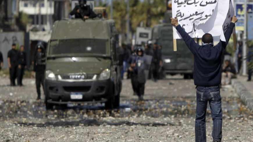 A protester opposing Egyptian President Mohamed Mursi holds up a sign during clashes in front of the Security Directorate in Port Said city, 170 km (105 miles) northeast of Cairo March 5, 2013. Egyptian security forces battled stone-throwing youths in the Suez Canal city of Port Said on Tuesday while in Cairo even police staged a protest, reflecting a country beset by discontent over a host of grievances. The sign reads "Port Said not thugs, this is our freedom".  REUTERS/Amr Abdallah Dalsh (EGYPT - Tags: P