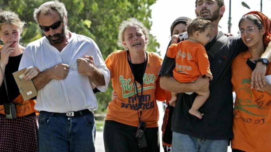 Jewish settlers cry as they walk to the synagogue for a ceremony before departing the Jewish settlement of Ganei Tal, in the Gush Katif settlement bloc, in the southern Gaza Strip, August 17, 2005. Israeli troops began the forced evacuation on Wednesday of thousands of Jewish settlers gripped by rage and anguish over their eviction from the Gaza Strip after nearly four decades of occupation. - RTXNOV8