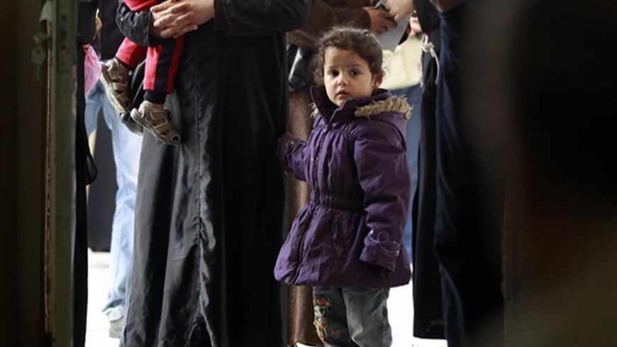 Syrian refugees stand as they wait to receive humanitarian aid shopping vouchers at a distribution center of the World Food Program (WFP) organization in Amman April 11, 2013. The U.N. refugee agency and the WFP are distributing shopping vouchers to 170,000 Syrian refugees in Jordan every month to mostly women and children. The shopping voucher program has allocated $5.5 million in vouchers for Syrian refugees in Jordan, according to a WFP official.  REUTERS/Muhammad Hamed (JORDAN - Tags: POLITICS SOCIETY I