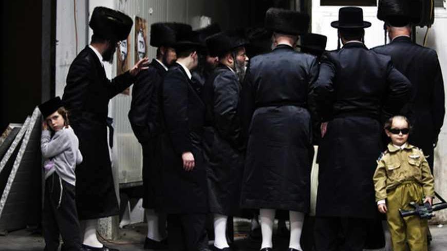 An Ultra-Orthodox Jewish boy dressed in a special costume as a soldier for Purim stands next to a group of adults in Bnei Brak February 23, 2013. Purim is a celebration of the Jews' salvation from genocide in ancient Persia, as recounted in the Book of Esther. REUTERS/Nir Elias (ISRAEL - Tags: RELIGION SOCIETY TPX IMAGES OF THE DAY) - RTR3E6W8