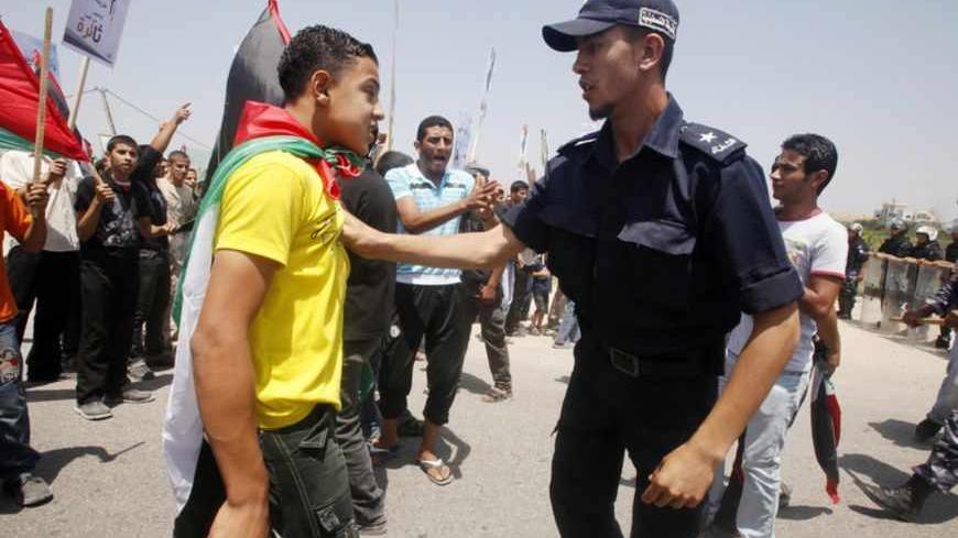 A Hamas policeman pushes back a Palestinian protester during a demonstration near the Erez border crossing between Israel and northern Gaza Strip June 5, 2011, marking the 44th anniversary of the start of a 1967 Middle East War, in which Israel captured East Jerusalem, the Gaza Strip, the West Bank and Golan Heights. REUTERS/Suhaib Salem (GAZA - Tags: POLITICS CIVIL UNREST ANNIVERSARY) - RTR2NB6A