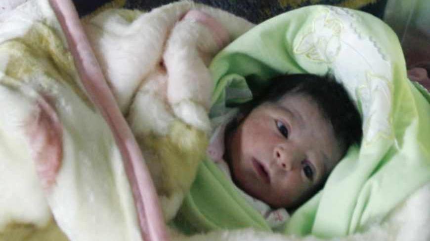 A newborn baby girl lies next to her mother in the maternity ward of Al-Hilal hospital in the West bank city of Ramallah October 30, 2011. The world's population will reach seven billion on Oct. 31, according to projections by the United Nations, which says this global milestone presents both an opportunity and a challenge for the planet. REUTERS/Mohamad Torokman (WEST BANK - Tags: HEALTH) - RTR2TFEF