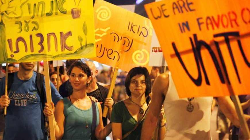 Israeli protesters hold placards as they march on a main road during a demonstration calling for social justice in Tel Aviv July 14, 2012. Some thousands of Israelis gathered in cities throughout the country to mark one year since the start of social protests demanding for more social welfare, local media reported. REUTERS/Amir Cohen (ISRAEL - Tags: CIVIL UNREST POLITICS SOCIETY) - RTR34XYI