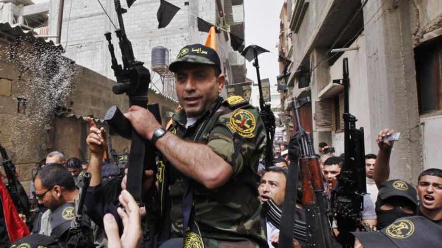 Freed Palestinian prisoner Ibrahim Baroud holds a gun as he carried on the shoulders of Islamic Jihad militants through crowds of people, as he arrives at his home in the northern Gaza Strip April 8, 2013. Baroud, who was convicted of his affiliation with the armed group of Islamic Jihad and for carrying out armed attacks against Israel, was released on Monday after serving 27 years in an Israeli jail, according to media reports.  REUTERS/Mohammed Salem (GAZA - Tags: POLITICS TPX IMAGES OF THE DAY) - RTXYD6