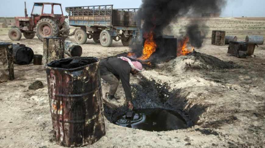 TO GO WITH AFP STORY BY JOSE MIGUEL CALATAYUD
A picture taken on April 15, 2013 shows a Syrian man in the Al Raqqa countryside, who until three months ago was a farmer, pouring crude oil brought from Deir Ezzor province into a pit where it will be distilled as part of the refining process to produce fuel. Final products such as benzine and diesel are then sold to locals. Deir Ezzor contains the largest energy reserves in Syria, which produced some 420,000 of barrels of oil a day before the United States and