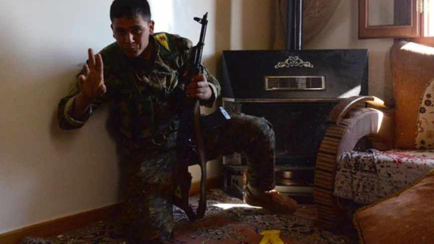A Kurdish fighter from the "Popular Protection Units" (YPG) gestures after firing towards Syrian government forces inside a building in the majority-Kurdish Sheikh Maqsud district of the northern Syrian city of Aleppo, on April 21, 2013. Syria's National Coalition head Ahmad Moaz al-Khatib has refiled his resignation and an interim leader is being sought, a fellow member and a source close to the main opposition group said. AFP PHOTO/MIGUEL MEDINA        (Photo credit should read MIGUEL MEDINA/AFP/Getty Ima