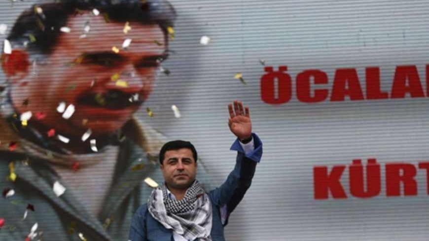 Selahattin Demirtas, co-chairman of the pro-Kurdish Peace and Democracy Party, greets his supporters during a rally to celebrate the spring festival of Newroz in Istanbul March 17, 2013. A picture of imprisoned PKK leader Abdullah Ocalan is seen in the background. REUTERS/Murad Sezer (TURKEY - Tags: POLITICS CIVIL UNREST) - RTR3F4BY