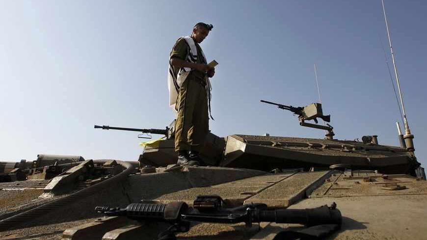 An Israeli soldier prays atop a tank close to the ceasefire line between Israel and Syria on the Israeli occupied Golan Heights May 6, 2013. Israel sought to persuade Syrian President Bashar al-Assad on Monday that its recent air strikes around Damascus did not aim to weaken him in the face of a more than two-year-old rebellion. REUTERS/Baz Ratner (ISRAEL - Tags: POLITICS MILITARY) - RTXZC75