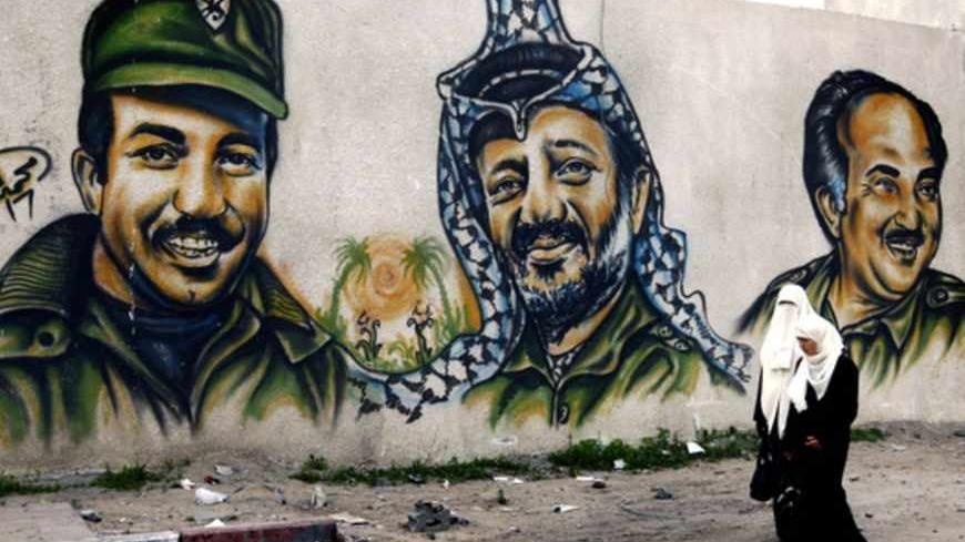 Palestinian women walk by the walls of the destroyed Hamas headquarters compound in Gaza January 24, 2009. The Hamas headquarters was repeatedly bombed during Israel's devastating three-week war. On the background are portraits of (L-R)  Khalil Al Wazir (second in command in Fatah movement, Yassir Arafat (Late Palestinian President) and Salah Khalaf  (co-founder of the Palestinian Liberation Organization), all deceased.    REUTERS/Yannis Behrakis (GAZA) - RTR23TCK