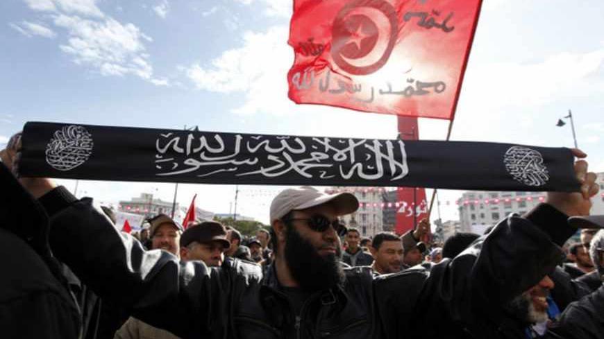 A man from the Salafist faction holds up a banner that reads "There is no god but God, and Muhammad is the messenger of God", on the second anniversary of the Tunisian Revolution at Avenue Habib Bourguiba in Tunis January 14, 2013. Thousands of Tunisians protested against the Islamist-led government on Monday, exactly two years after the overthrow of President Zine El Abidine Ben Ali in a popular revolt that inspired others across the Arab world. In the same street, about 2,000 supporters of the Islamic-led