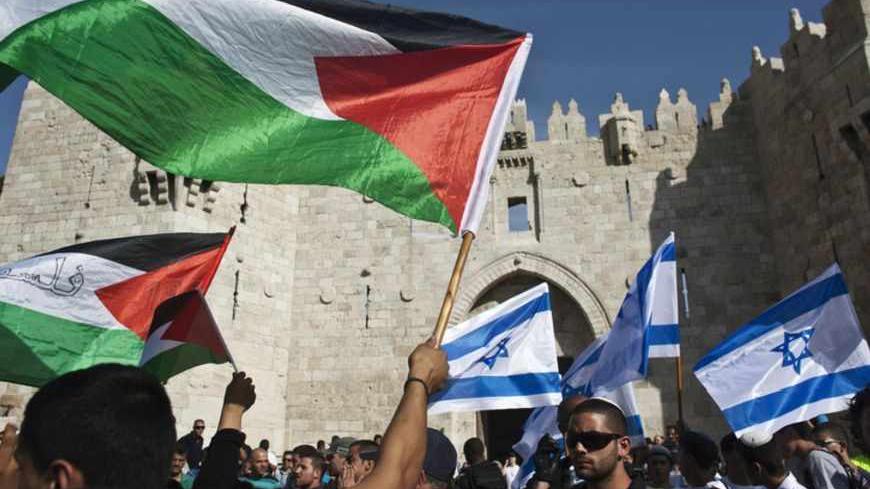 Palestinian protesters wave Palestinian flags as Israelis carrying Israeli flags walk past in front of the Damascus Gate outside Jerusalem's Old City during a parade marking Jerusalem Day May 8, 2013. Jerusalem Day marks the anniversary of Israel's capture of the Eastern part of the city during the 1967 Middle East War. In 1980, Israel's parliament passed a law declaring united Jerusalem as the national capital, a move never recognised internationally. There were confrontations on Wednesday between Muslims