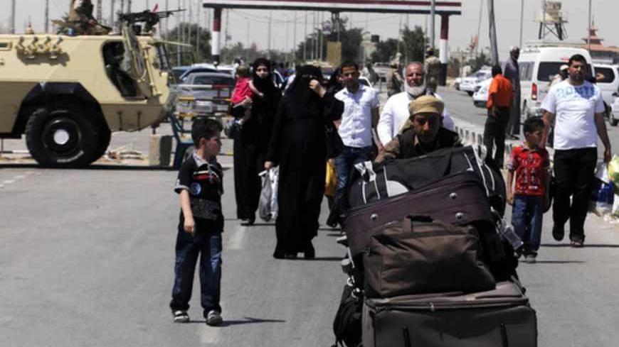 Palestinian travellers pass an Egyptian soldier standing guard on the Egyptian side of the Rafah border, to cross over to Gaza at Rafah city, some 350 km (217 miles) northeast of Cairo, May 22, 2013. Seven members of the Egyptian security forces kidnapped by Islamist militants in Sinai last week were freed on Wednesday and President Mohamed Mursi announced a new crackdown on lawlessness in the desert peninsula. Their abduction underlined the threat posed by jihadists who became active in a security vacuum t