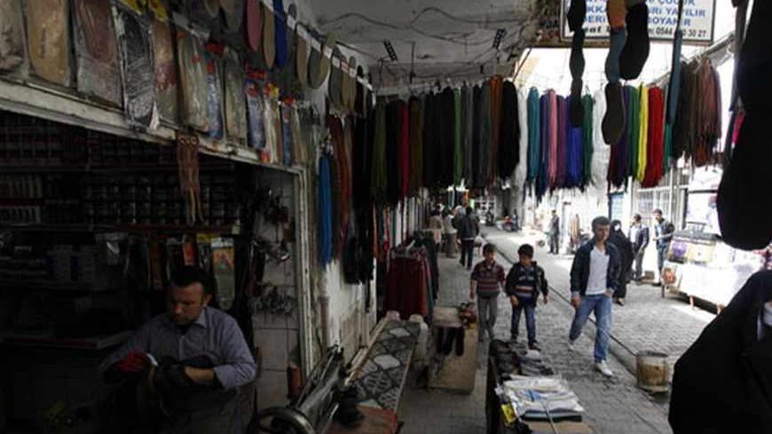 A man repairs shoes in his shop as locals pass through on a street in the town of Cizre in Sirnak province, near the border with Syria March 23, 2013. Turkey's fledgling peace process with the Kurdistan Workers Party (PKK) militant group is all over the headlines. After three decades of war, 40,000 deaths and a devastating impact on the local economy, everybody seems ready for peace. Pro-Kurdish politicians are focused on boosting minority rights and stronger local government for the Kurds, who make up abou