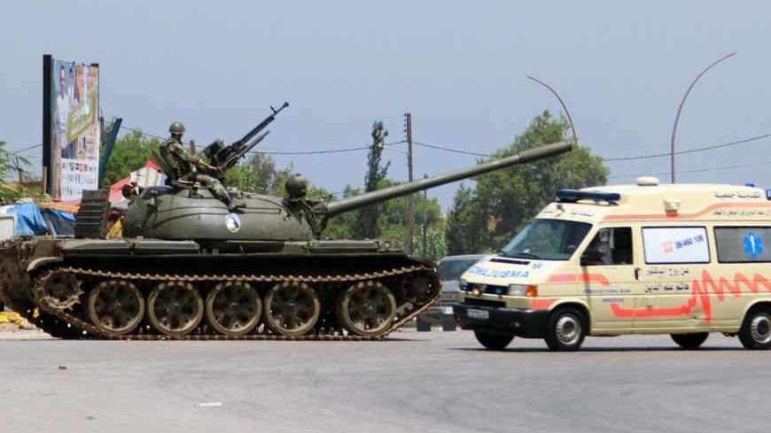 A Lebanese army soldier is seen atop his tank as an ambulance travels past in Tripoli May 20, 2013. Three people have been killed and about 40 wounded in two days of fighting in Lebanon's northern city of Tripoli, security sources said on Monday, as sectarian violence spilled over from the civil war in Syria.   REUTERS/Omar Ibrahim (LEBANON - Tags: POLITICS CIVIL UNREST MILITARY) - RTXZTWK