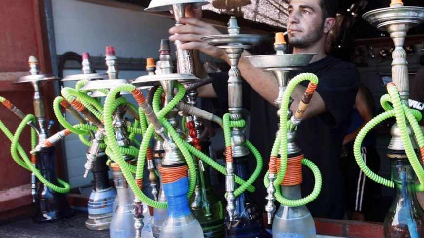 A Palestinian vendor prepares water pipes at his shop on the beach of Khan Younis in the southern Gaza Strip May 31, 2009. Sunday marks World No Tobacco Day. REUTERS/Ibraheem Abu Mustafa (GAZA ANNIVERSARY HEALTH) - RTR2443D