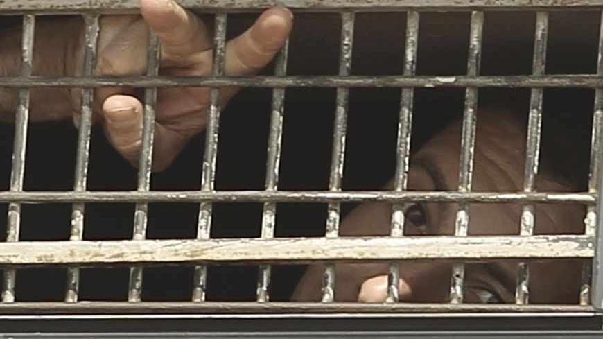 A Palestinian prisoner gestures from the window of a bus as it leaves Nafha Prison in the southern town of Mitzpe Ramon October 16, 2011, before a prisoner swap that is expected to take place on Tuesday. Israel took the first steps on Sunday in the prisoner swap with Hamas in which hundreds of Palestinian militants will be exchanged for captive Israeli soldier Gilad Shalit. REUTERS/Ilan Assayag (ISRAEL - Tags: POLITICS CIVIL UNREST TPX IMAGES OF THE DAY) ISRAEL OUT. NO COMMERCIAL OR EDITORIAL SALES IN ISRAE