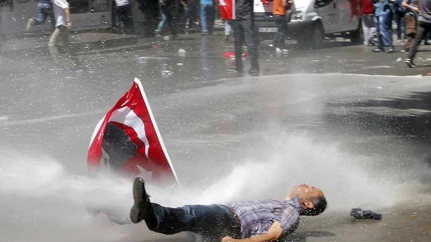A man is hit by a jet of water as riot police use a water cannon to disperse demonstrators during a protest against Turkey's Prime Minister Tayyip Erdogan and his ruling Justice and Development Party (AKP) in central Ankara June 1, 2013. Erdogan made a defiant call for an end to the fiercest anti-government demonstrations in years on Saturday, as thousands of protesters clashed with riot police in Istanbul and Ankara for a second day. REUTERS/Umit Bektas (TURKEY - Tags: POLITICS CIVIL UNREST TPX IMAGES