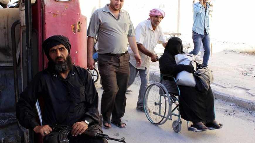 A Free Syrian Army fighter sits at his checkpoint as civilians walk along a passageway separating Aleppo's Bustan al-Qasr, which is under the rebels' control and Al-Masharqa neighborhood, an area controlled by the regime, June 5, 2013. Picture taken June 5, 2013. REUTERS/Aref Hretani (SYRIA - Tags: POLITICS CONFLICT MILITARY CIVIL UNREST) - RTX10DHX
