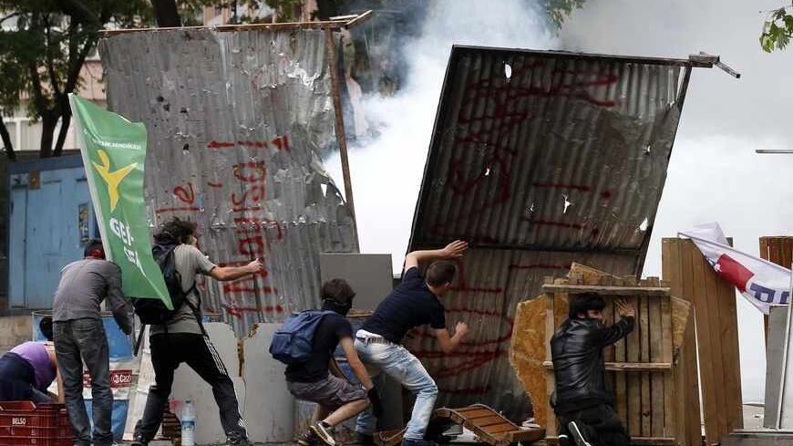 Demonstrators stand in front of a make shift shield during clashes with Turkish riot police in central Ankara June 2, 2013. Erdogan accused Turkey's main secular opposition party on Sunday of stirring a wave of anti-government protests, as tens of thousands regrouped in Istanbul and Ankara after a lull and trouble flared again in the capital. Police used tear gas on protesters in Ankara but the clashes were relatively minor compared with major violence in Turkey's biggest cities on the previous two days. RE