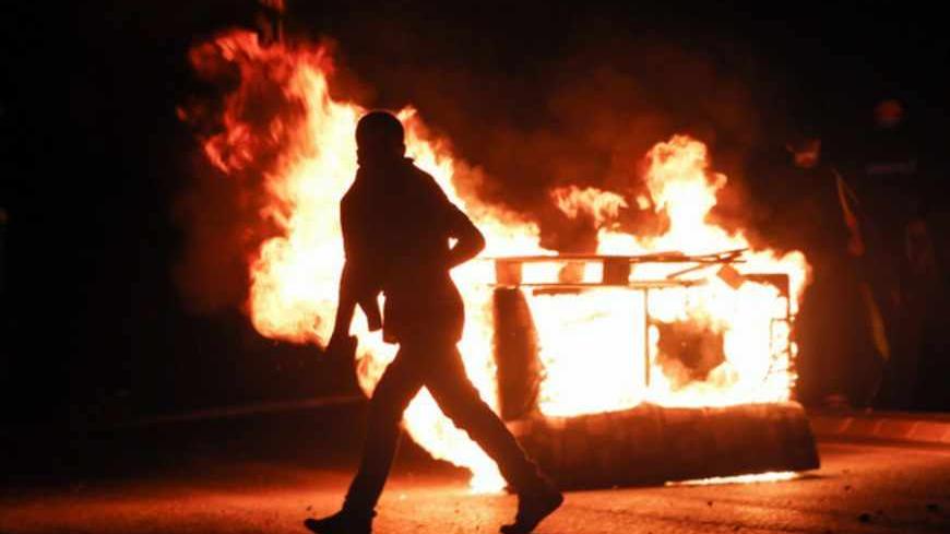 A protester runs by a burning barricade during clashes with riot police in Istanbul's Gazi neighborhood June 8, 2013. REUTERS/Yannis Behrakis (TURKEY - Tags: CIVIL UNREST POLITICS TPX IMAGES OF THE DAY) - RTX10GV1