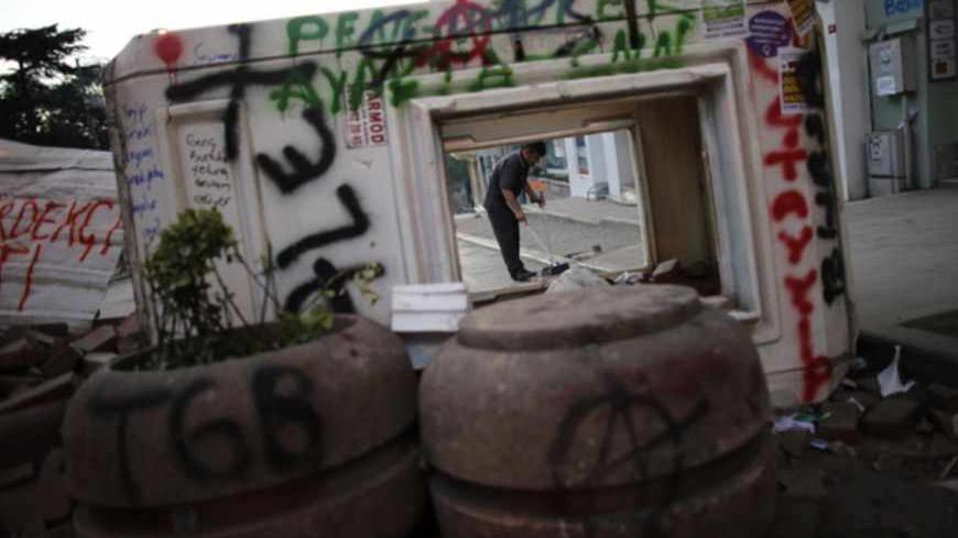 A hotel employee is pictured behind a barricade as he cleans the street near Taksim square in central Istanbul June 10, 2013. Turkey's Prime Minister Tayyip Erdogan warned protesters who have taken to the streets across Turkey demanding his resignation that his patience has its limits and compared the unrest with an army attempt six years ago to curb his power. REUTERS/Murad Sezer (TURKEY  - Tags: POLITICS CIVIL UNREST) - RTX10I8R