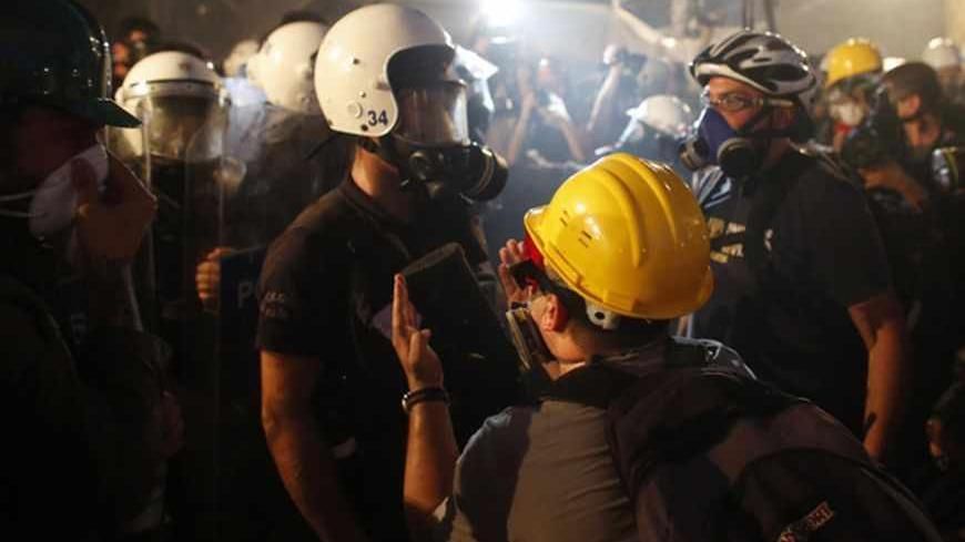 A protester reacts as riot police order them to evacuate Gezi Park in central Istanbul June 15, 2013. Thousands of people took to the streets of Istanbul overnight on Sunday, erecting barricades and starting bonfires, after riot police firing teargas and water cannon stormed a park at the centre of two weeks of anti-government unrest. Lines of police backed by armoured vehicles sealed off Taksim Square in the centre of the city as officers raided the adjoining Gezi Park late on Saturday, where protesters ha
