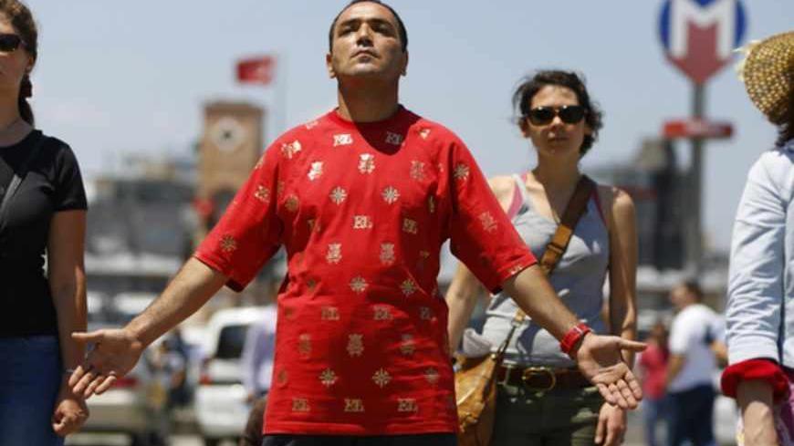 People stand during a silent protest at Taksim Square in Istanbul June 18, 2013. A Turkish man has staged an eight-hour silent vigil on Istanbul's Taksim Square, scene of violent clashes between police and anti-government protesters in recent weeks, inspiring hundreds of others to follow his lead. REUTERS/Marko Djurica (TURKEY - Tags: CIVIL UNREST POLITICS) - RTX10RSA