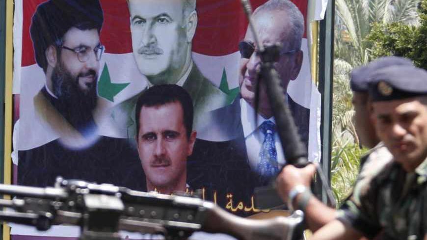 Lebanese Army soldiers stand atop of their army vehicle as they secure the area, during a protest organised by Syrians living in Lebanon in support of Syria's regime, in Sidon, southern Lebanon, May 12, 2013. The poster in the background depicts Syria's late President Hafez al-Assad (C, top), father of current President Bashar al-Assad (C, bottom), Lebanon's Hezbollah leader Sayyed Hassan Nasrallah (L) and Lebanon's parliamentary speaker Nabih Berri (R). REUTERS/Ali Hashisho (LEBANON - Tags: POLITICS CIVIL 