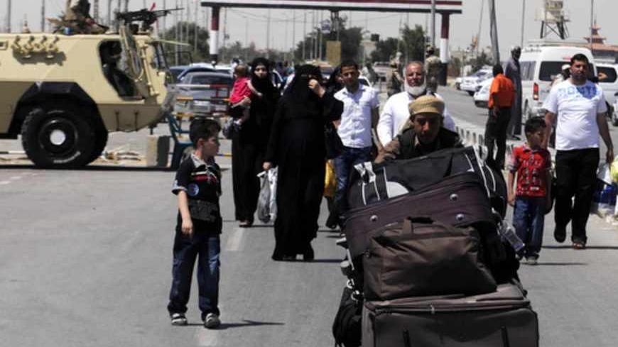 Palestinian travellers pass an Egyptian soldier standing guard on the Egyptian side of the Rafah border, to cross over to Gaza at Rafah city, some 350 km (217 miles) northeast of Cairo, May 22, 2013. Seven members of the Egyptian security forces kidnapped by Islamist militants in Sinai last week were freed on Wednesday and President Mohamed Mursi announced a new crackdown on lawlessness in the desert peninsula. Their abduction underlined the threat posed by jihadists who became active in a security vacuum t