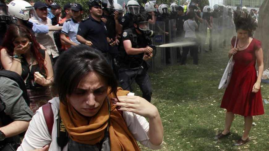 A Turkish riot policeman uses tear gas as people protest against the destruction of trees in a park brought about by a pedestrian project, in Taksim Square in central Istanbul May 28, 2013. REUTERS/Osman Orsal (TURKEY - Tags: POLITICS CIVIL UNREST ENVIRONMENT TPX IMAGES OF THE DAY) - RTX103XA