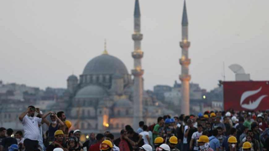 Anti-government protesters, with the New mosque in the background, gather over the Galata bridge in Istanbul June 16, 2013. Turkish Prime Minister Tayyip Erdogan rallied hundreds of thousands of supporters at an Istanbul parade ground on Sunday as riot police fired teargas several kilometres away in the city centre to disperse anti-government protesters. Riot police fired teargas into side streets around the central Taksim Square as he spoke, trying to prevent protesters from regrouping after hundreds were