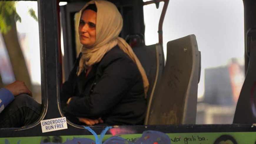 A woman wearing a traditional head-scarf sits inside a damaged bus used by anti-government protesters as a barricade in Istanbul's Taksim square June 10, 2013. REUTERS/Yannis Behrakis (TURKEY - Tags: CIVIL UNREST POLITICS) - RTX10IVO