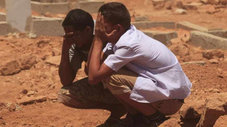 Men grieve over a grave at the funerals for those killed in Saturday's clashes at the Libya Shield brigade headquarters, in Benghazi June 9, 2013. Libya's army will take control of a militia's bases in the eastern city of Benghazi after clashes in which 31 people were killed, an army spokesman said on Sunday. Fighting broke out on Saturday at the headquarters of the Libya Shield brigade when protesters demanded the disbanding of the militias, whose continued existence nearly two years after the fall of Muam