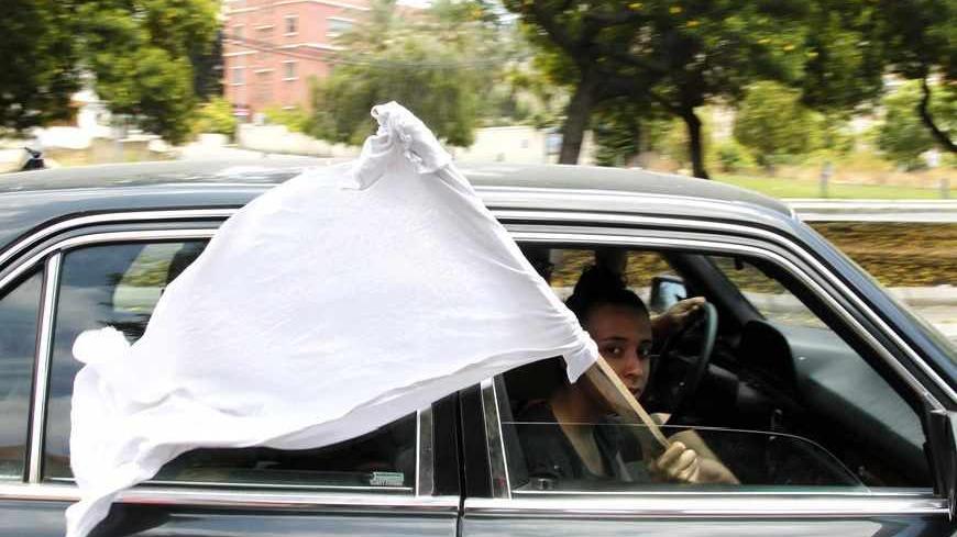 A girl holds a white flag to show that civilians are in the car, during clashes between Lebanese army soldiers and gunmen of hardline Sunni Muslim cleric Sheikh Ahmed al-Assir, in Abra near Sidon, southern Lebanon, June 24, 2013. Lebanese soldiers fought Sunni Muslim gunmen in the southern city of Sidon on Monday in one of the deadliest outbreaks of violence fuelled by sectarian divisions over the civil war in neighbouring Syria. REUTERS/Ali Hashisho (LEBANON - Tags: POLITICS CIVIL UNREST MILITARY) - RTX10Y