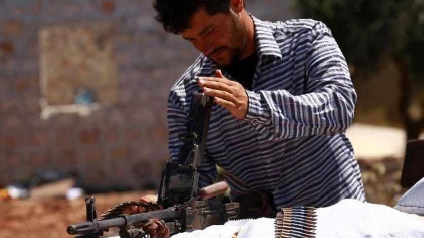 A Free Syrian Army member inspects his weapon beside a checkpoint to siege the Kurdish city of Afrin, which is under the control of the Kurdistan Workers' Party (PKK), in the Aleppo countryside June 30, 2013. REUTERS/Hamid Khatib (SYRIA - Tags: POLITICS CIVIL UNREST CONFLICT) - RTX117H8