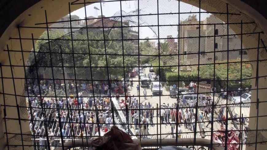 Protesters are seen through a damaged window from inside the Muslim Brotherhood's headquarters after it was attacked by protesters opposing Egyptian President Mohamed Mursi in Cairo's Moqattam district July 1, 2013. The Brotherhood said on Monday that armed men who ransacked its national headquarters had crossed a red line of violence, and the movement was considering action to defend itself. Hundreds of people threw petrol bombs and rocks at the building, which caught fire as guards and Brotherhood members