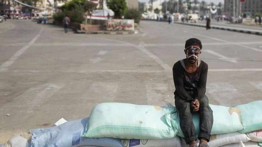 A protester, with his forehead painted with the colours of the Egyptian flag, sits on sand bags used to secure the entrance of Tahrir square, in Cairo, July 9, 2013. REUTERS/ Asmaa Waguih (EGYPT - Tags: POLITICS CIVIL UNREST) - RTX11HQ0