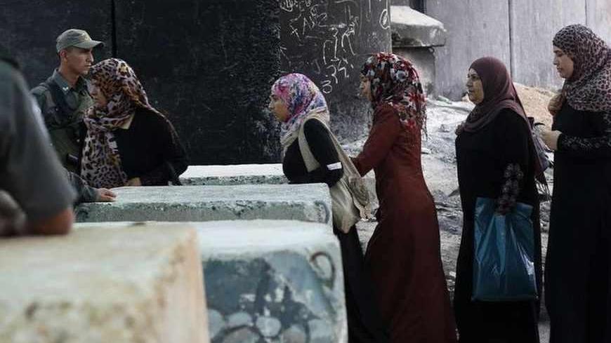 Palestinian women walk past Israeli border policemen as they cross at Qalandiya checkpoint outside the West Bank city of Ramallah, on the first Friday of the holy month of Ramadan July 12, 2013. REUTERS/Mohamad Torokman (WEST BANK - Tags: MILITARY RELIGION) - RTX11KOH