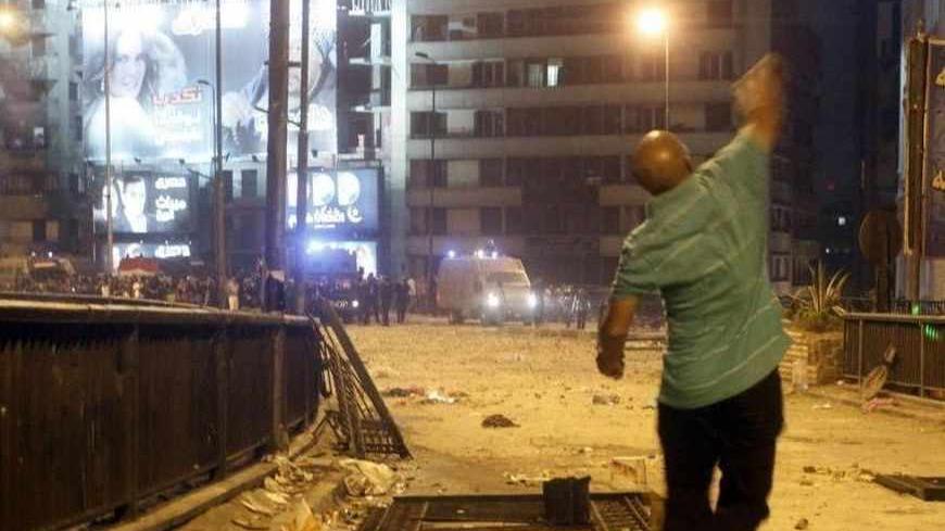 A supporter of deposed Egyptian President Mohamed Mursi throws stones at riot police during clashes in the Ramsis square area in central Cairo July 15, 2013. Egyptian police and protesters clashed in central Cairo early on Tuesday after fights broke out between supporters of ousted Islamist President Mohamed Mursi and locals angered when they tried to block major thoroughfares crossing the River Nile. REUTERS/Asmaa Waguih  (EGYPT - Tags: POLITICS CIVIL UNREST) - RTX11NYQ