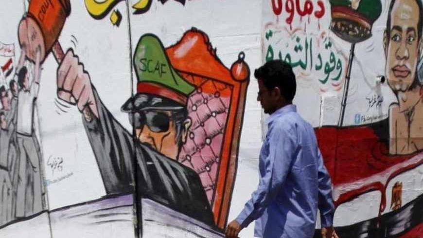 A member of the Muslim Brotherhood and supporter of ousted Egyptian President Mohamed Mursi walks in front of graffiti depicting Abdel Fattah al-Sisi, army commander and defense minister, around Cairo University and Nahdet Misr Square in Giza July 23, 2013. Six people were killed in Cairo on Tuesday in violence between supporters and opponents of Mursi, state-run media reported. The violence broke out before dawn near a Brotherhood protest at Cairo University, where Mursi supporters have been camped out sin