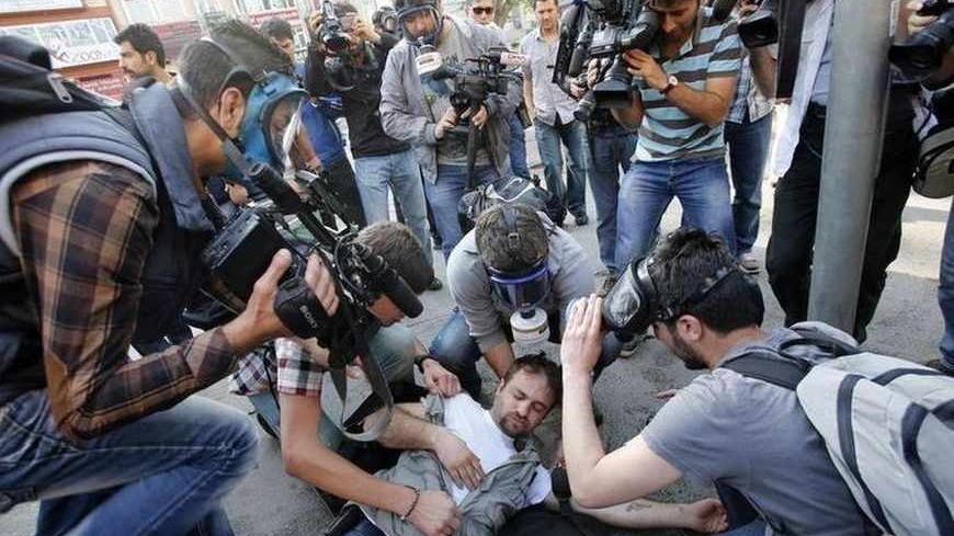 An injured journalist is filmed and helped by his colleagues during clashes between riot police and May Day protesters in central Istanbul May 1, 2013. Turkish riot police clashed with thousands of May Day protesters in Istanbul on Wednesday, firing water cannon and tear gas at crowds that tried to break through barricades to reach the city's main square, witnesses said. The incidents followed the pattern of recent years, when May Day demonstrations in Turkey's largest city have often been marked by clashes