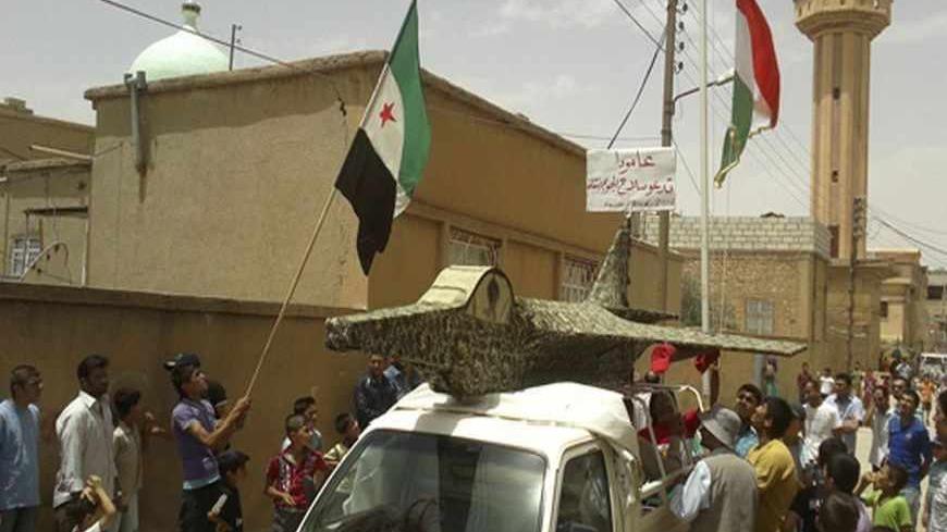 Demonstrators display a model of a MiG-21 fighter plane during a demonstration against Syria's President Bashar al-Assad in Amuda June 22, 2012. Syrian air force pilot Colonel Hassan Hamada flew his MiG-21 fighter plane over the border to Jordan and was granted political asylum on Thursday, the first defection with a military aircraft since the start of the uprising against President Bashar al-Assad.  REUTERS/Shaam News Network/Handout (SYRIA - Tags: POLITICS CIVIL UNREST TRANSPORT) FOR EDITORIAL USE ONLY. 