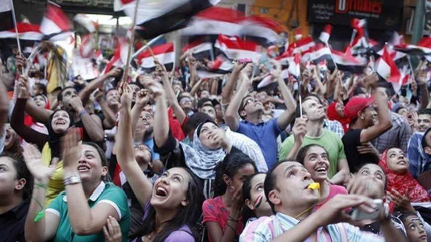 Anti-Mursi protesters look up at a military helicopter over the area as protesters chant slogans at a massive protest for the second day at a main street in Alexandria, July 1, 2013. Egypt's armed forces handed Islamist President Mohamed Mursi a virtual ultimatum to share power on Monday, giving feuding politicians 48 hours to compromise or have the army impose its own roadmap for the country.  REUTERS/Asmaa Waguih (EGYPT - Tags: POLITICS CIVIL UNREST) - RTX1197O