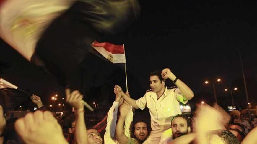 A policeman (C) cheers with protesters, who are against Egyptian President Mohamed Mursi, as they dance and react in front of the Republican Guard headquarters in Cairo July 3, 2013. Egypt's armed forces overthrew elected Islamist President Mohamed Mursi on Wednesday and announced a political transition with the support of a wide range of political, religious and youth leaders. A statement published in Mursi's name on his official Facebook page after head of Egypt's armed forces General Abdel Fattah al-Sisi