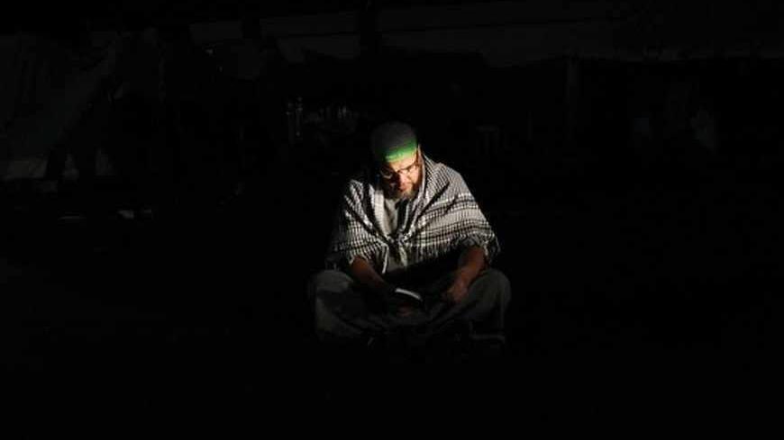 A supporter of deposed Egyptian President Mohamed Mursi reads the Koran at the Rabaa Adawiya square where Mursi's supporters are camping in Cairo July 9, 2013. Egypt's interim head of state has set a speedy timetable for elections to drag the Arab world's biggest country from crisis, after the military ouster of Mursi last week sparked a wave of bloody protests. REUTERS/Khaled Abdullah (EGYPT - Tags: POLITICS CIVIL UNREST RELIGION TPX IMAGES OF THE DAY) - RTX11HD4