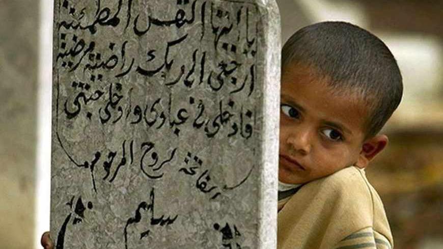 A Palestinian boy looks from behind a tombstone at the El  Sohada cemetary (martyrs' cemetery) outside Gaza city after the last prayer of Ramadan November 25, 2003. [Palestinians like Muslims all over the world today celebrate the first day of the Muslim's holiday of Eid El-Fitr folowing the end of the fasting month of Ramadan.] - RTXMB3X