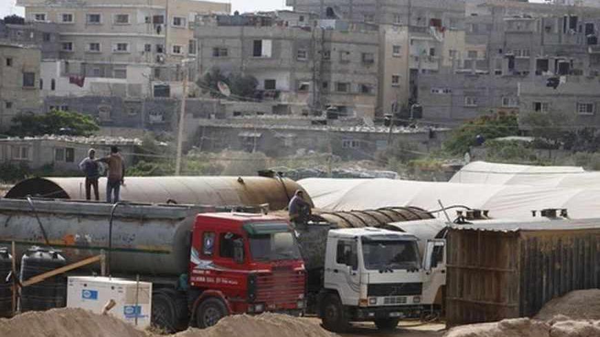 Palestinians wait as they fill tankers with fuel on the border between Egypt and southern Gaza Strip July 8, 2013. Armed men launched a series of attacks on Sunday on security checkpoints in the North Sinai towns of Sheikh Zuweid and El Arish close to Egypt's border with Israel and the Gaza Strip, and one soldier was killed. The Rafah border crossing between Egypt and Gaza Strip remained closed since Friday. REUTERS/Ibraheem Abu Mustafa (GAZA - Tags: POLITICS CIVIL UNREST MILITARY ENERGY) - RTX11GFQ